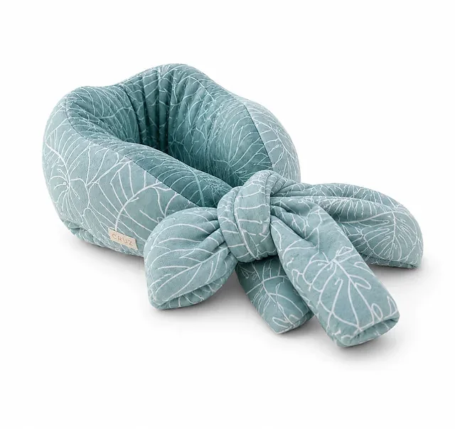 Sea-green padded Cruz travel pillow with a white leaf-outline print, its long ends tied in a soft knot.